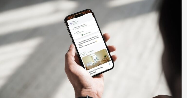 Persona che consulta il booking engine Slope sullo smartphone per visualizzare una prenotazione alberghiera, scegliere la camera e gestire il soggiorno online.